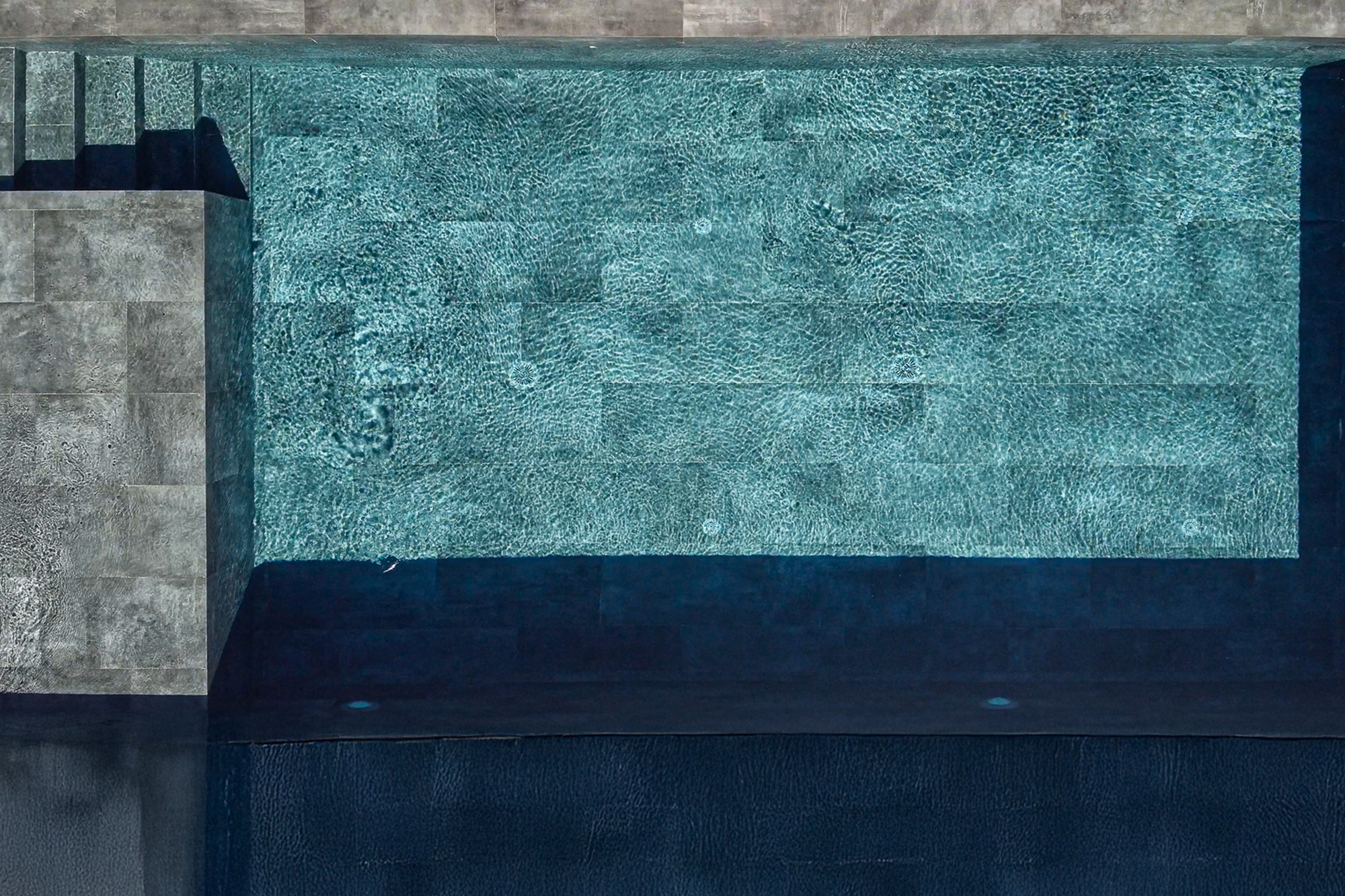 Infinity swimming pool with natural black stone finishes in luxury villa