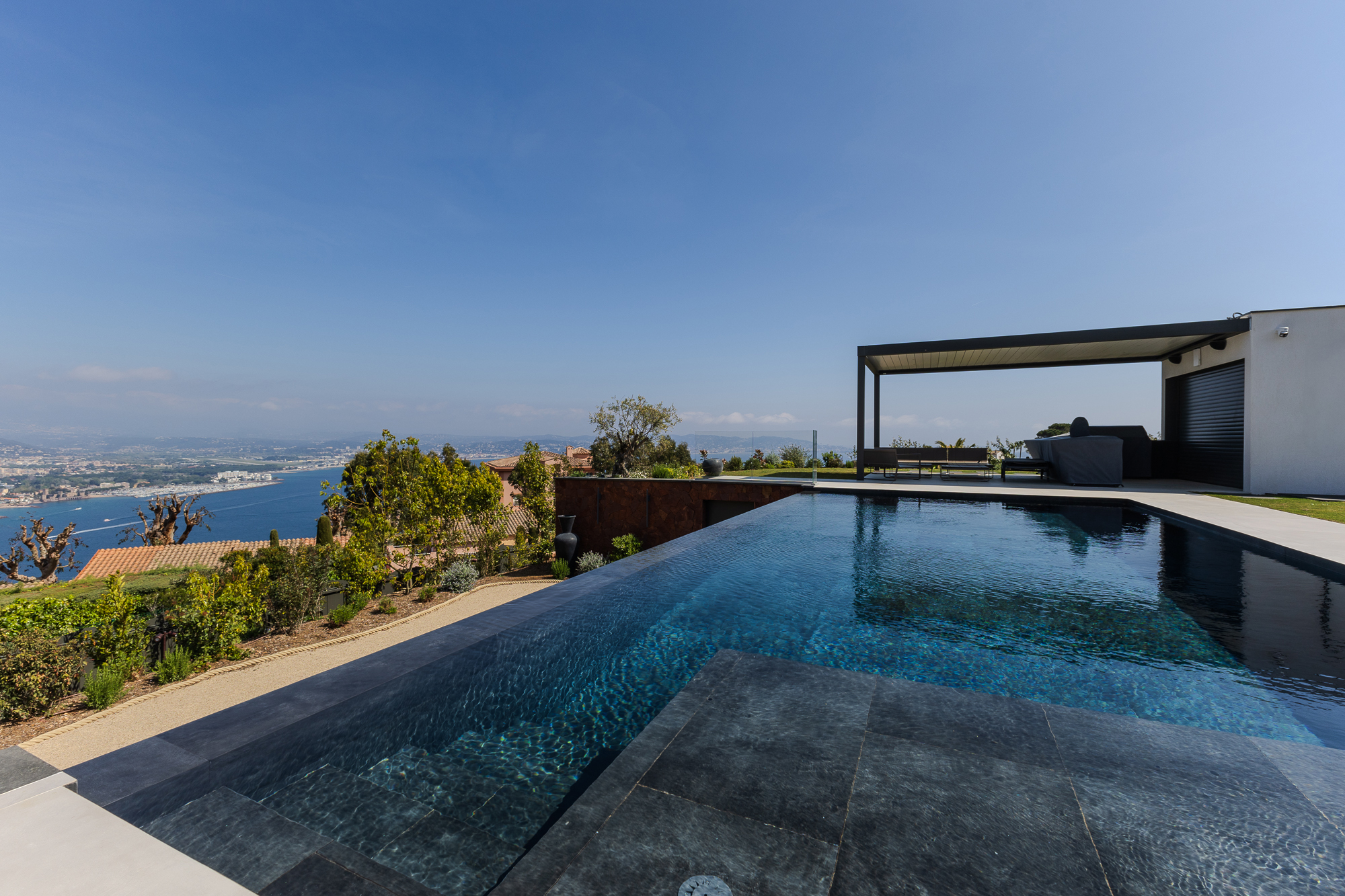 High-end outdoor lounge area with pool house and shaded terrace.